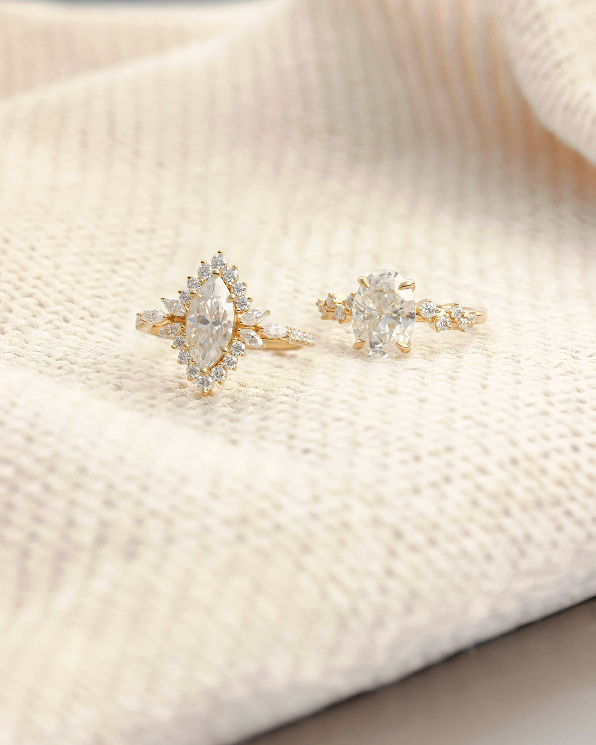Two gold diamond engagement rings on cream knit fabric